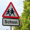 An image of a school sign held on by tape.